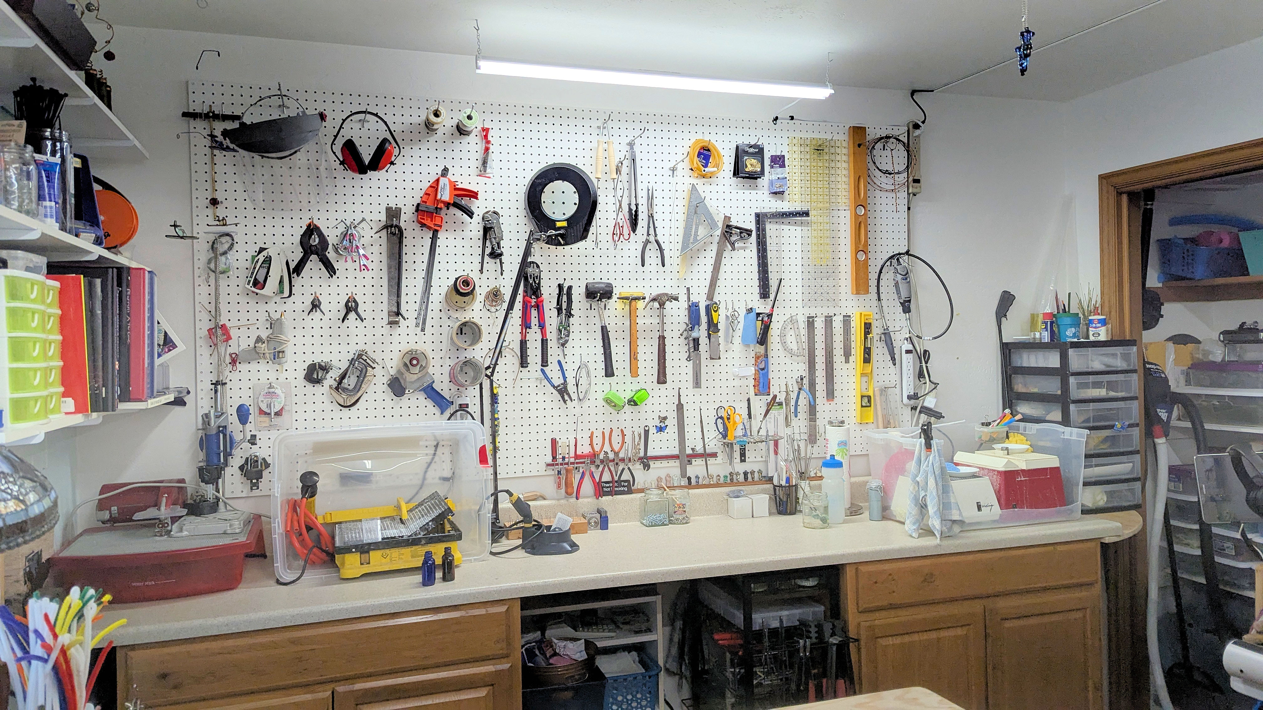 Standing work bench with pegboard wall for tool storage, wet saws and grinders